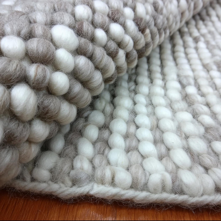 Translation missing: es.Handmade chunky wool rug with cream and beige pom pom design for cozy, natural home décor