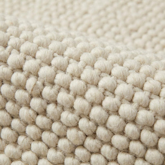 Translation missing: es.Close up of chunky knitted wool rug showing thick natural yarn and soft woven texture
