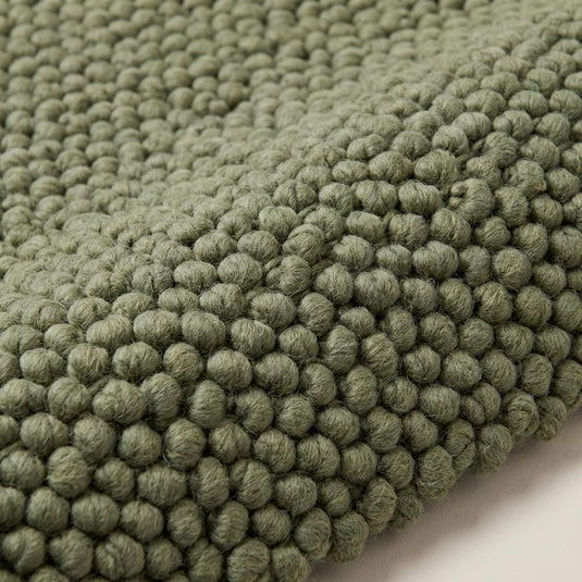 Translation missing: es.Close-up of chunky handwoven wool rug showing thick braided texture and soft sage green color
