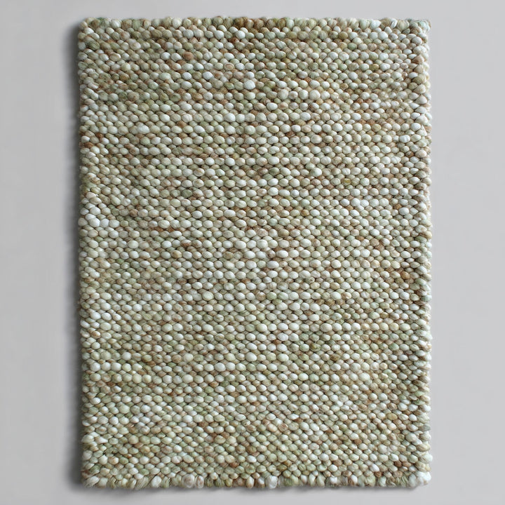 Translation missing: es.Top view of a handmade chunky wool rug with handwoven pebble texture in sage green, cream and tan — felted wool rectangle ideal for nursery or entryway