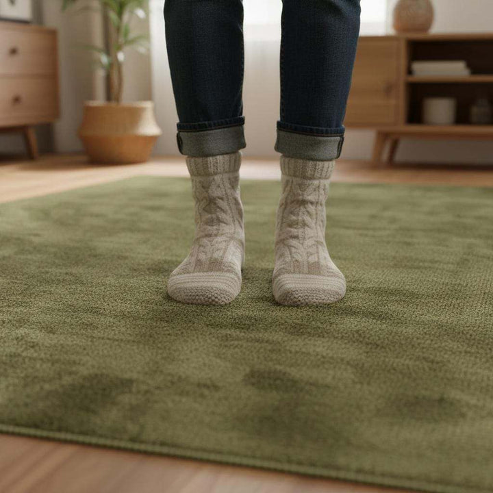 Translation missing: en.Minimalist Scandinavian style living room with light oak flooring and a deep olive green area rug providing colour and texture