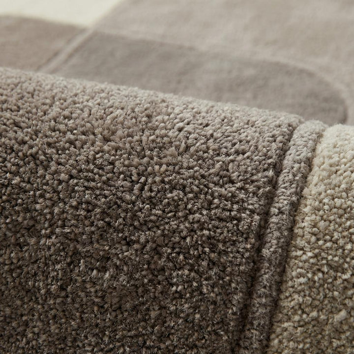 Translation missing: en.Close-up of plush modern rug fibers showing sculpted high-low pile, soft dense texture, and carved geometric pattern in cream and taupe neutral tones