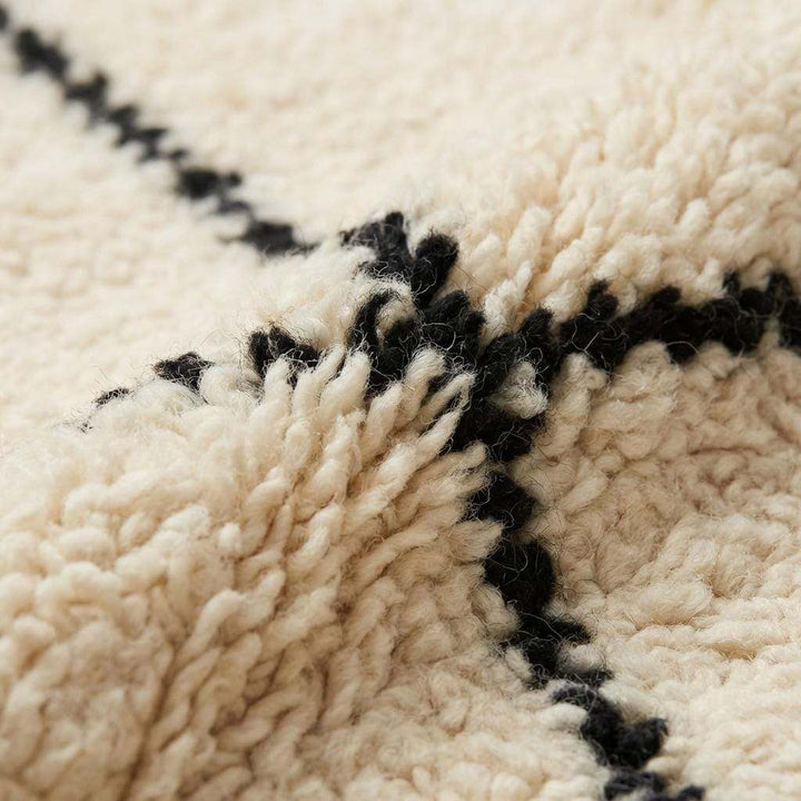 Translation missing: es.Close-up of plush ivory rug texture with black line pattern