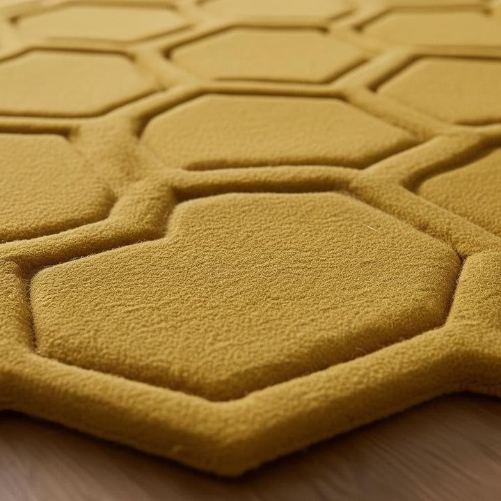 Translation missing: es.Close-up of raised hexagon texture and sculpted borders on mustard yellow rug