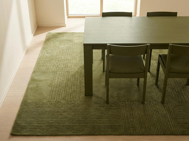 Translation missing: en.Corner detail of olive green textured area rug showing carved square pattern and clean finished edge