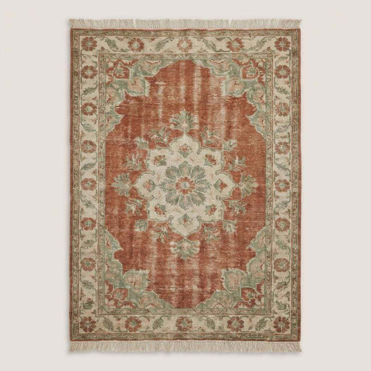 Translation missing: es.Vintage style Oushak wool rug with floral border pattern and muted earthy colors on dark wooden floor