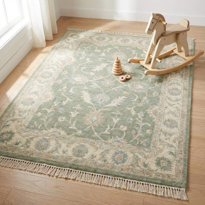 Translation missing: es.Green wool area rug styled on dark wood floor with neutral furniture and soft lighting