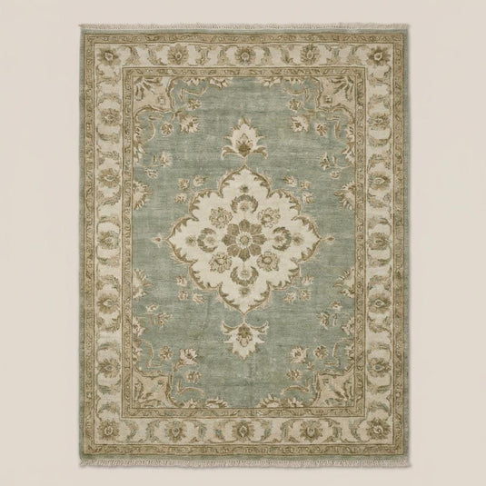 Translation missing: fr.Traditional Oushak style floral medallion rug in sage green and beige tones on dark wooden flooring