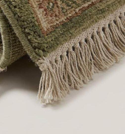 Translation missing: es.Close-up of hand knotted wool pile showing individual knots, natural wool texture, and soft sage green tones