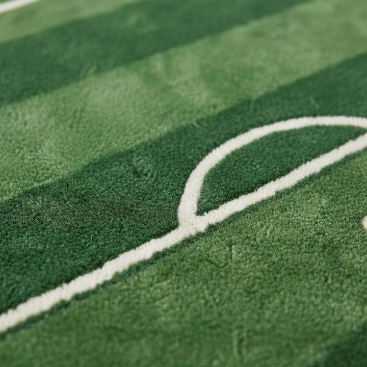 Translation missing: es.Close-up of plush tufted soccer rug showing soft green pile texture, white field line detailing, and neatly finished edges highlighting craftsmanship and pile height