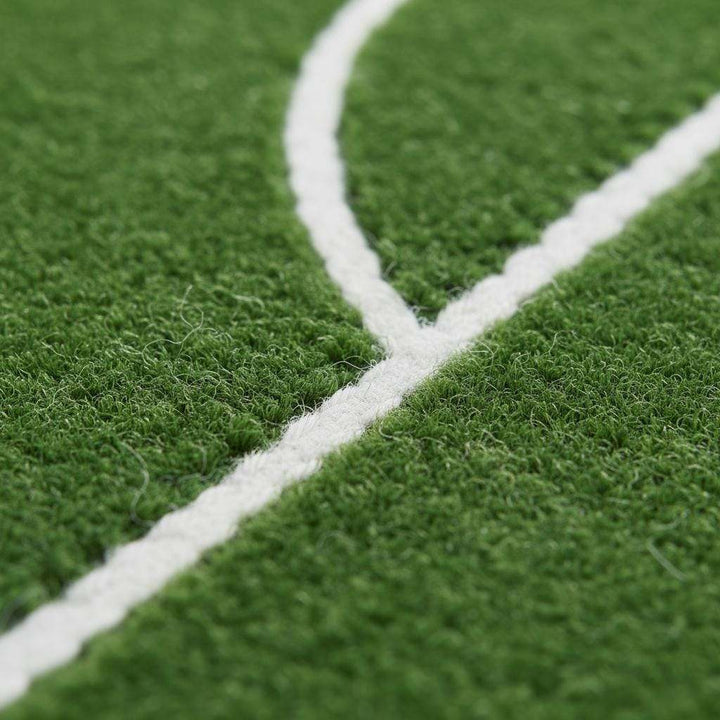 Translation missing: es.Close-up of soccer pitch rug surface with bright green field and sharp white boundary markings