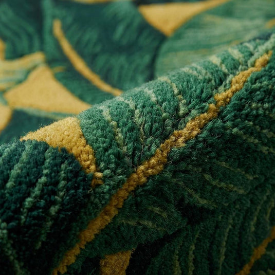 Translation missing: es.Close-up of sculpted tropical leaf rug showing high-pile tufted texture, carved green foliage detailing, and rich mustard background, highlighting plush fibers and dimensional craftsmanship