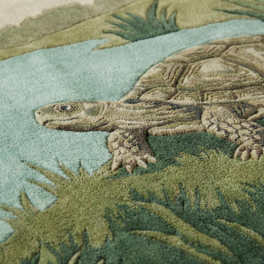 Translation missing: es.Close-up of hand tufted turtle rug showing carved wool texture, raised detailing, plush pile fibers, and botanical grass design in earthy green tones