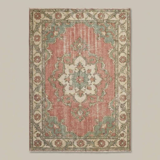 Translation missing: es.Soft pink and sage green vintage wool rug styled in bright living room with wooden flooring
