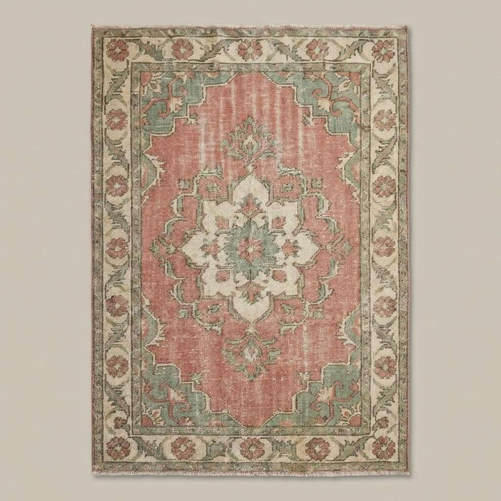 Translation missing: es.Soft pink and sage green vintage wool rug styled in bright living room with wooden flooring