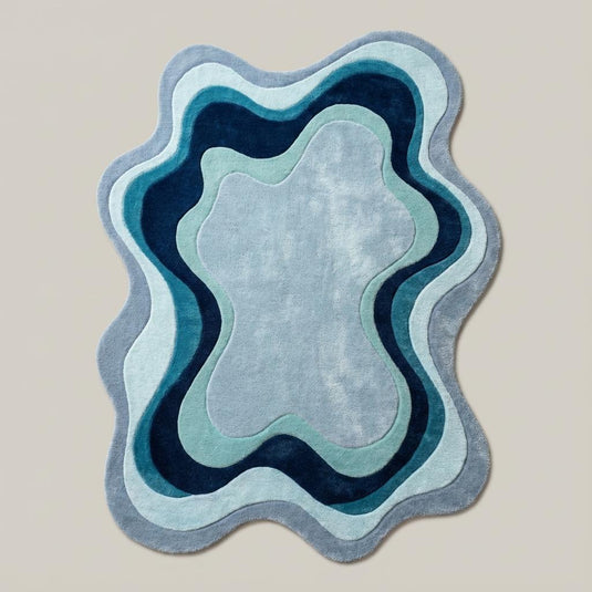 Translation missing: es.Organic shape abstract rug featuring layered blue waves styled on wooden flooring in a cozy contemporary home décor space