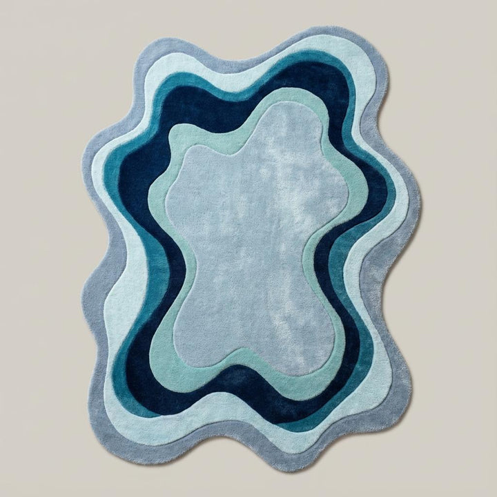 Translation missing: es.Organic shape abstract rug featuring layered blue waves styled on wooden flooring in a cozy contemporary home décor space