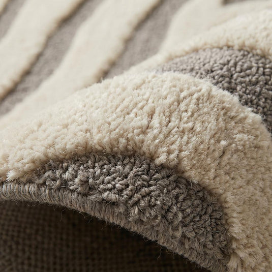Translation missing: es.Close-up of high low hand tufted wool texture showing raised ivory carved zebra pattern over dense gray base pile