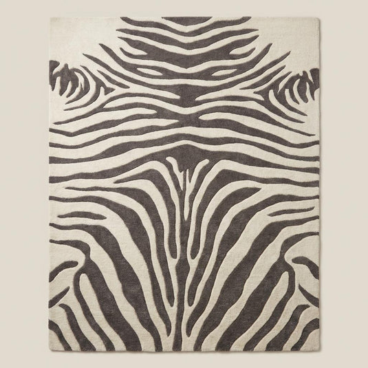 Translation missing: es.Rectangular zebra pattern wool rug with bold animal print design styled under accent chair on light wood flooring