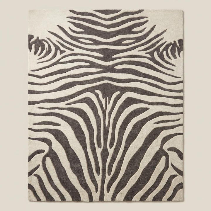 Translation missing: es.Rectangular zebra pattern wool rug with bold animal print design styled under accent chair on light wood flooring