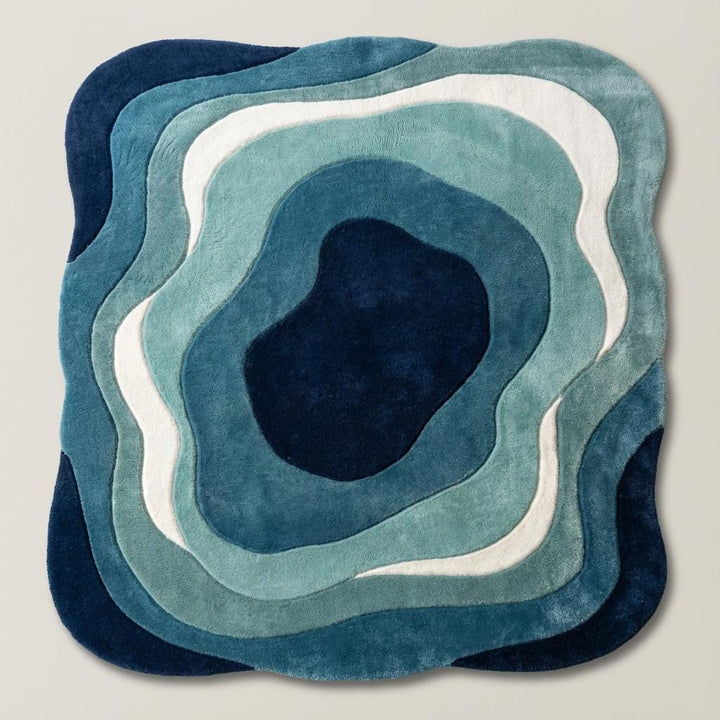 Translation missing: en.Artistic blue carpet with topographic-inspired layers, placed in a mid-century modern room with wooden furniture and greenery