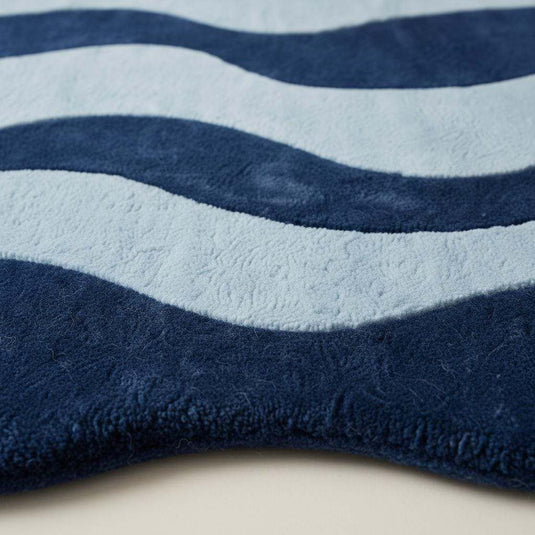 Translation missing: es.Irregular shaped curvy area rug in deep blue tones on hardwood floor, adding modern artistic style to living space